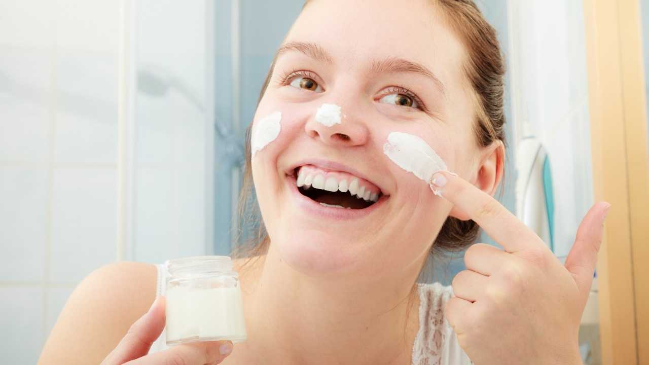 a girl applying skin whitening cream on her face