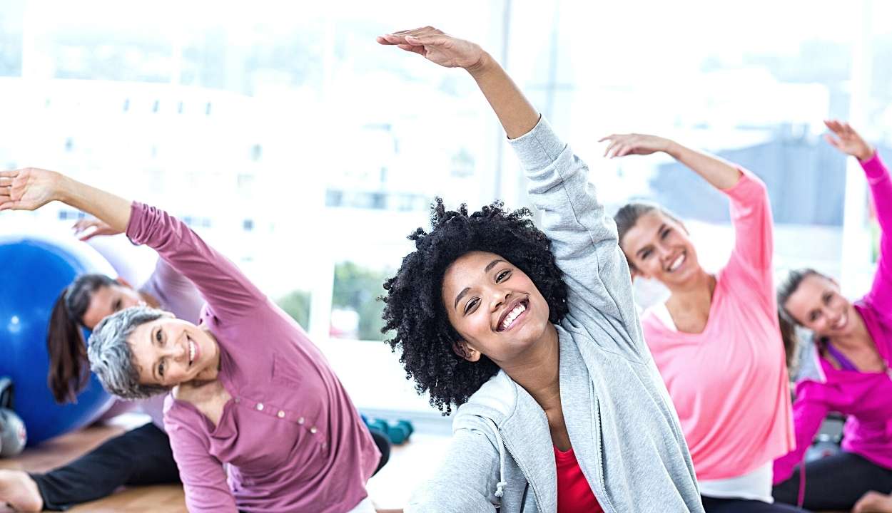 Cheerful women exercising with arms raised in a fitness studio