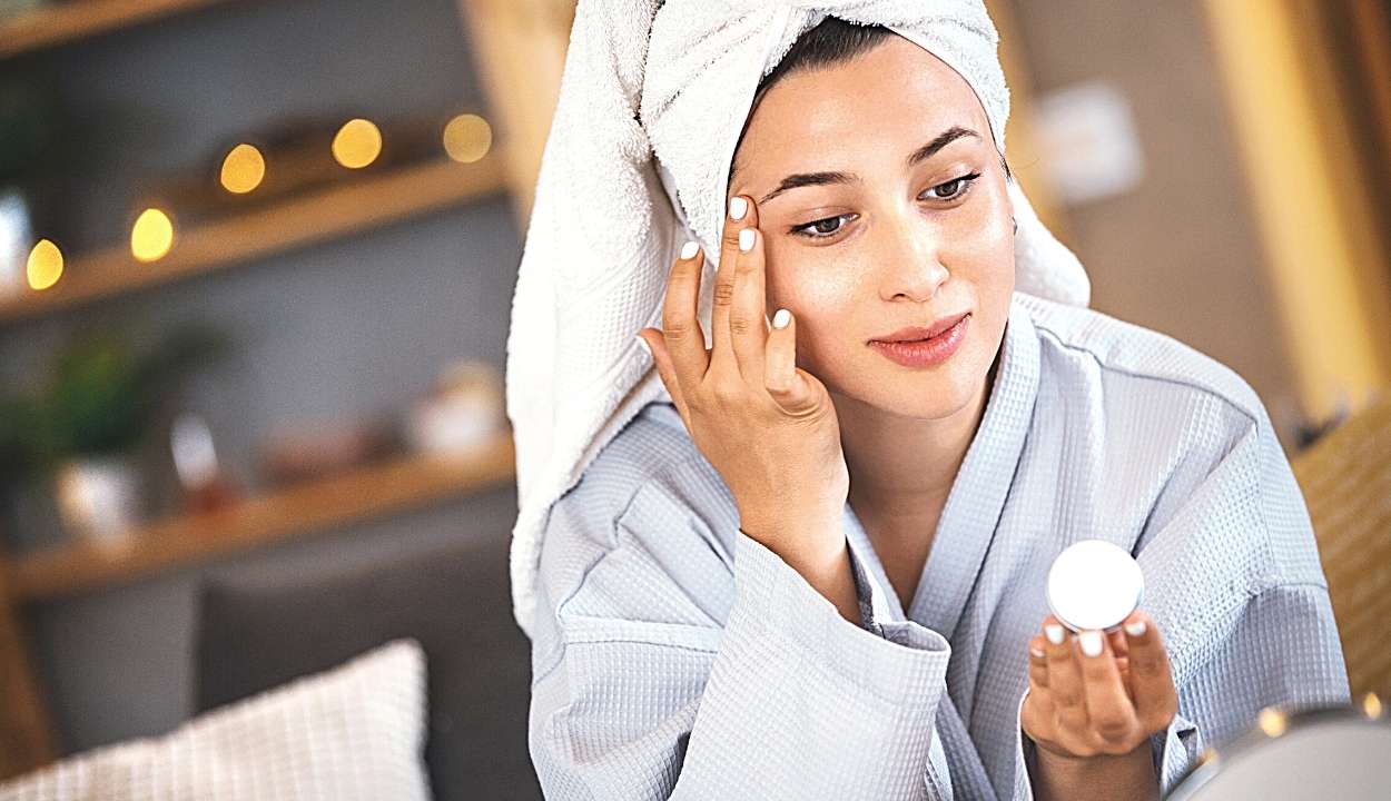 a girl applying face cream while looking in the mirror