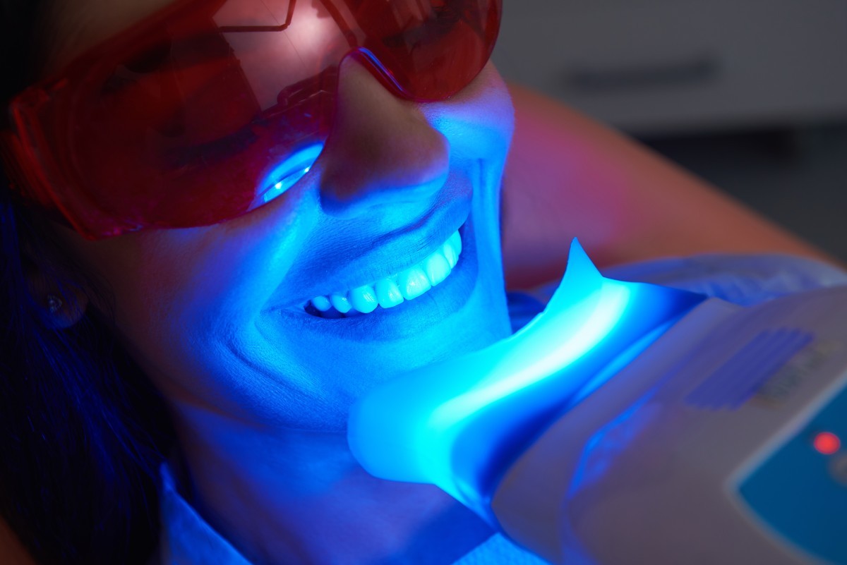 Close up of happy girl getting laser treatment for teeth whitening