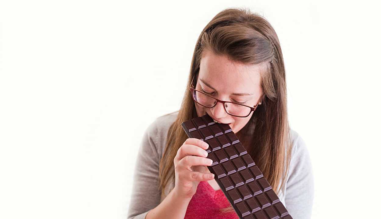 a girl taking a bite from a chocolate bar