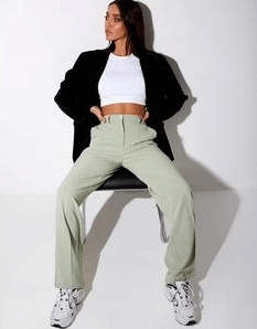 a girl wearing a white shirt under a black jacket and sage green pants